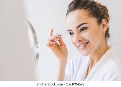 Young Woman Plucking Eyebrows With Tweezers 