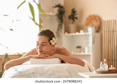 Young woman with plumeria flower lying on couch in spa salon - Powered by Shutterstock