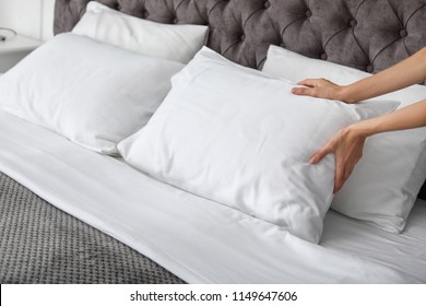 Joven desplumando almohada blanca en la cama, encerrada