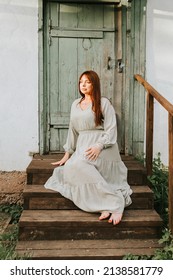 Young Woman Plus Size Model Sit Near Country House In Park Next To Blooming Lilac Tree, Concept Of Spring, Golden Hour, Barefoot