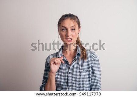 Young woman pointing on something below her, isolated on grey background