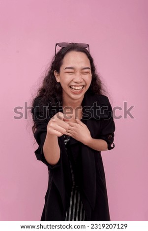A young woman pointing and proceeds to belittle someone. Isolated on a light pink background.