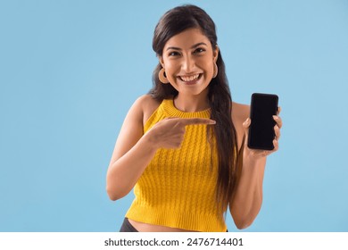 A young woman pointing towards her mobile phone.