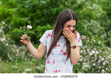 Young Woman With Pollen Allergy Holding A Flower And Saying No.. Young Woman With Pollen And Grass Allergies. Flowering Trees In Background. Spring Seasonal Allergies And Health Problems.