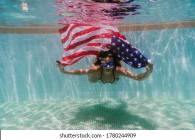 young woman in a pool holding american flag underwater. 4th july independence day concept. Summertime - Powered by Shutterstock
