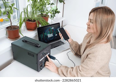 Young woman with portable power station at table in office. - Shutterstock ID 2282865021