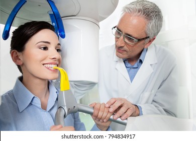 Young woman portrait having panoramic digital X-ray of her teeth with a middle age doctor in the dental office.