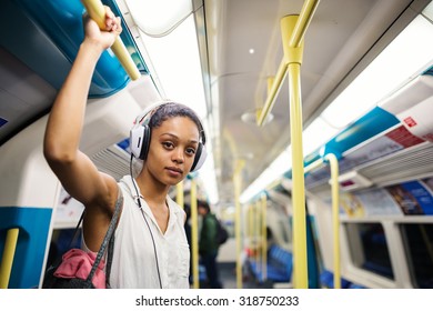 Young Woman Portrait Inside Underground In London Listening To Music With Earphones.