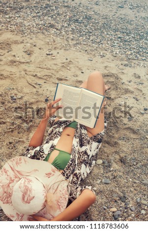 Young woman portrait reading book on the beach in Summer day