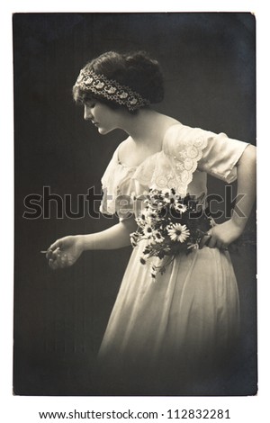 young woman posing with daisy flowers. vintage picture from 1913