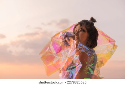 Young woman posing with holographic foil against sunset sky. Dreamy self expression concept fashion portrait - Shutterstock ID 2278325535
