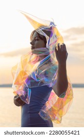 Young woman posing with holographic foil against sunset sky. Dreamy self expression concept fashion portrait	 - Shutterstock ID 2280055421