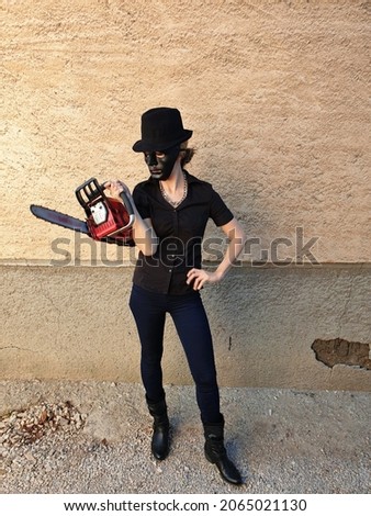 young woman posing near broken wall. girl wearing halloween costume for party. scary or funny. celebrating american holidays. october 31. november 1 lady with chain saw. killer in mask. 