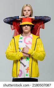 Young Woman Posing Near Man In Panama Hat And Windbreaker Isolated On Grey