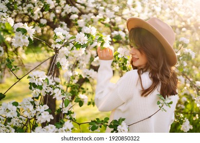 Young woman posing in spring blossom flowers in blooming garden. Female beauty, fashion. City lifestyle. 