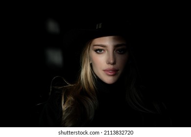 Young Woman Posing At Studio Over Black Background. Light And Shadow. Fashion Portrait Of Beautiful Woman With Dark Light On Face. Beautiful Girl With Beauty Face, Closeup.