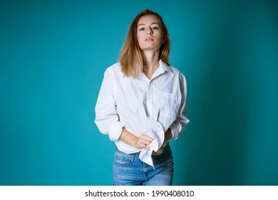 Young woman posing in white shirt and jeans on blue background