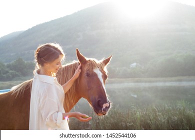 young woman posing with wild horse in the field against the lake