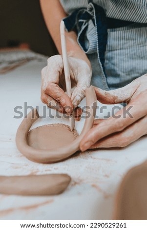 Young woman potter working with clay in a workshop. Close up of female hands. Selective focus.