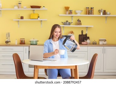 Young woman pouring boiled water from electric kettle into cup in kitchen - Powered by Shutterstock