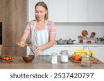 Young woman pouring chia seeds into glass in kitchen