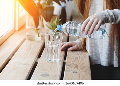 Young Woman Pouring Fresh Drink Water From Blue Plastic Bottle Inside