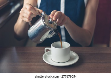 A young woman is pouring herself a cup of coffee in a diner - Powered by Shutterstock
