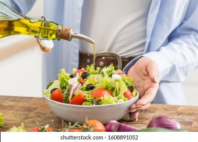 Young Woman Pouring Olive Oil In To The Salad. Healthy Lifestyle Eating Concept.