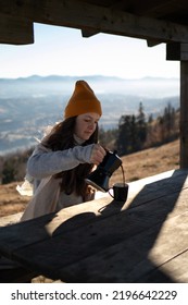 A Young Woman Pouring Out Coffee From A Moka Pot Into A Cup In Outdoors House In Front Of A Mountains Landscape