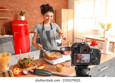 Young Woman Pouring Pasta With Sauce While Recording Video Class In Kitchen