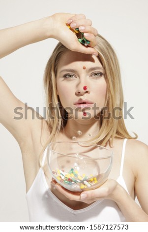 Young woman pouring pills into glass bowl in studio