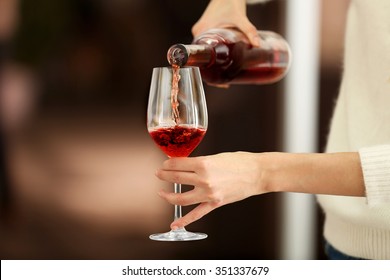 Young woman pouring pink wine into glass on blurred background - Shutterstock ID 351337679