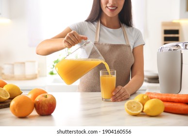 Young woman pouring tasty fresh juice into glass at table in kitchen, closeup - Powered by Shutterstock