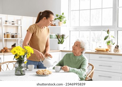 Young woman pouring tea into cup for her grandmother in kitchen - Powered by Shutterstock