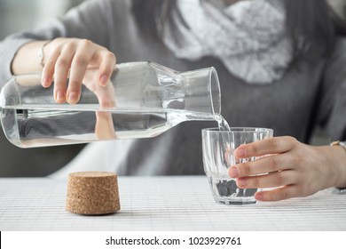 Young Woman Pouring Water From Bottle To Glass