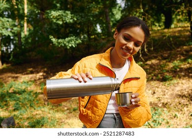 A young woman pours a warm beverage from a thermos, surrounded by colorful autumn foliage while hiking. - Powered by Shutterstock