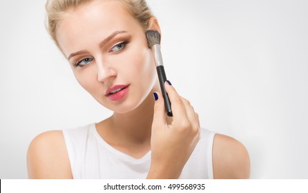 Young woman powders face brush