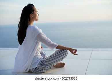 young woman practice yoga meditaion on sunset with ocean view in background - Powered by Shutterstock