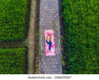 Young Woman Practice Yoga Outdoor In Rice Fields In The Morning During Wellness Retreat In Bali. View From The Drone