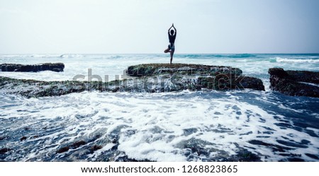 Young woman practice yoga at the seaside coral cliff edge