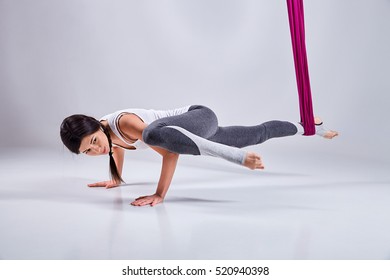 Young woman practices aerial different inversion anti-gravity yoga with a hammock in a white studio. Concept of a mental and physical health an harmony living