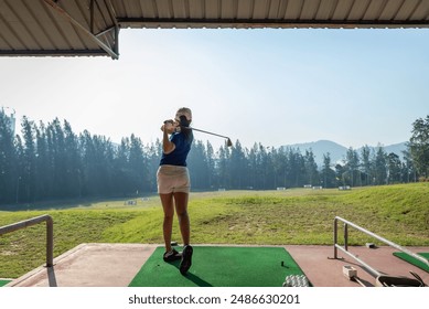 Young woman practices her golf swing on driving range Young girls practicing driving range. - Powered by Shutterstock