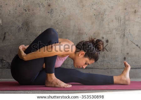Young woman practicing advance yoga in front of a urban wall 