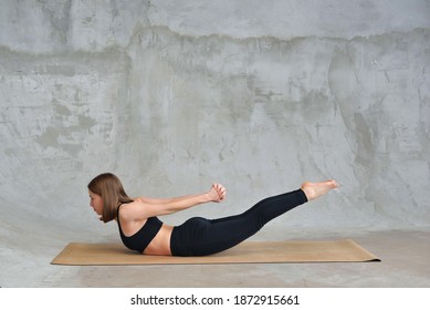 Young Woman Practicing Advanced Yoga In Sports Black Jersey In The Studio. Superman Pose. Viparita Shalabhasana