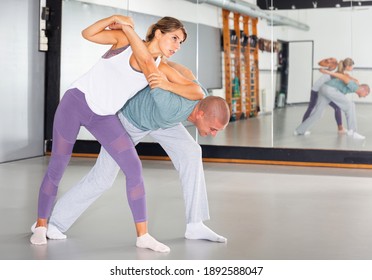 Young woman practicing basic protection skills with man during self defense course in gym - Powered by Shutterstock