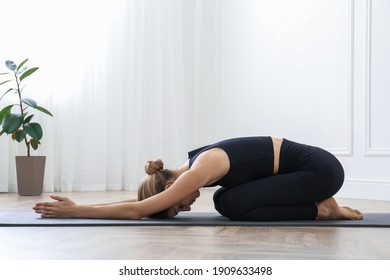 Young Woman Practicing Extended Child Asana In Yoga Studio. Utthita Balasana Pose