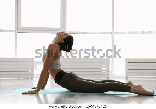 Young woman practicing high cobra asana in yoga\
studio. Bhujangasana pose