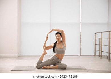 Young woman practicing mermaid asana in yoga studio. Eka Pada Rajakapotasana pose