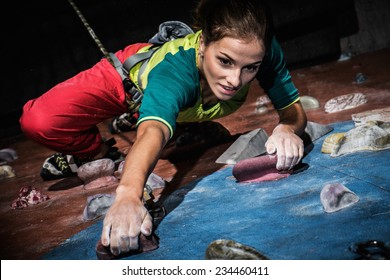 Young woman practicing rock-climbing on a rock wall indoors - Shutterstock ID 234460411