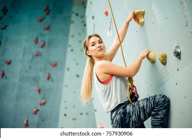 Young woman practicing rock-climbing on a rock wall indoors - Powered by Shutterstock